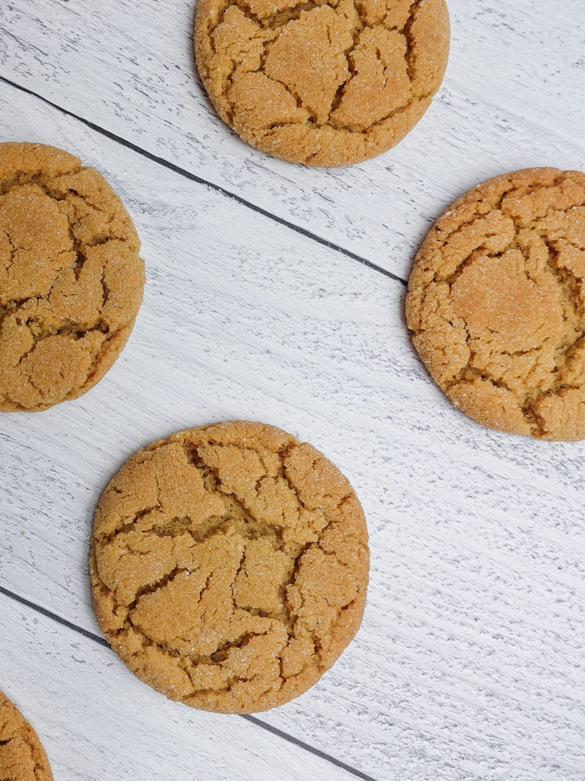 Delicious Peanut Butter Cookies with a sugar coating laid out on a white wood board counter top.